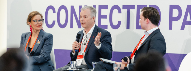 Three presenters on stage during The 2025 SUMMIT