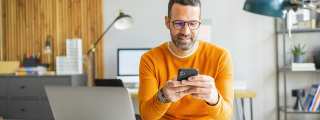 A person sitting at a desk while using their phone